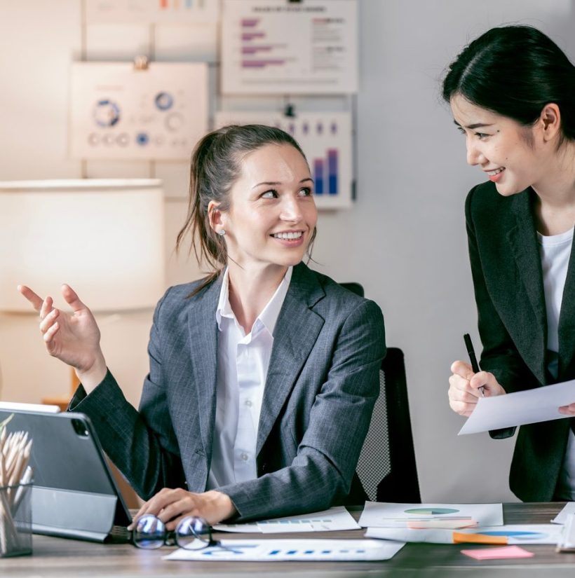 Happy young woman entrepreneurs smiling while working together in a modern workspace. Happy young woman entrepreneurs smiling while working together in a modern workspace.